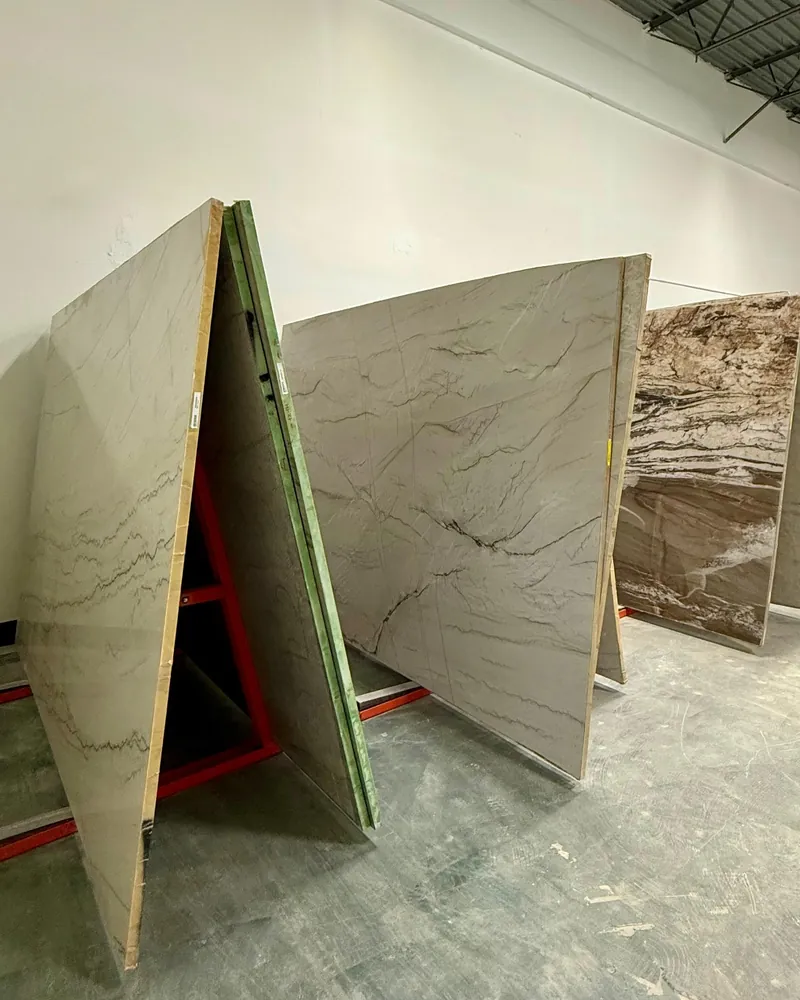 Stone slabs standing on red A-frame racks in a white-walled slab room