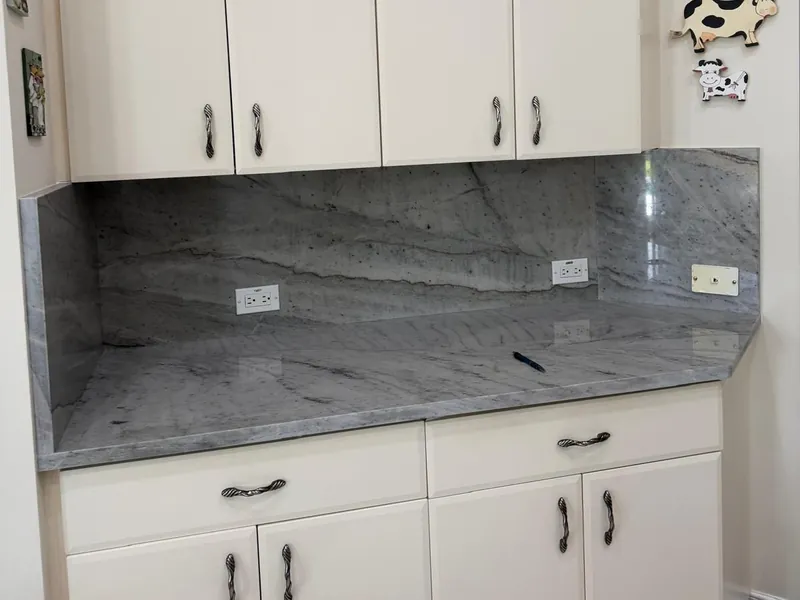 Stone backsplash up to the wall cabinets, with a side return and openings for the outlets