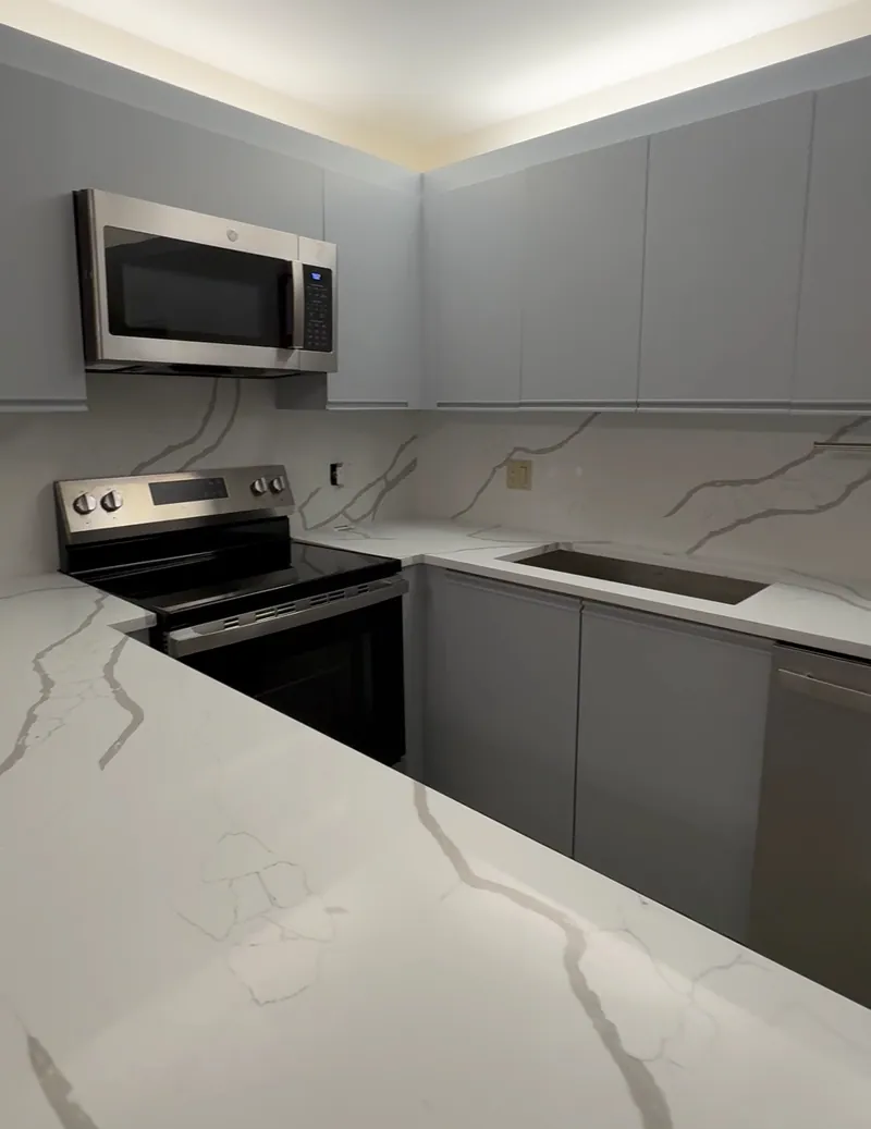 Full-height backsplash with bold gray veining around the range, microwave and the sink cutout, under gray flat-panel cabinets