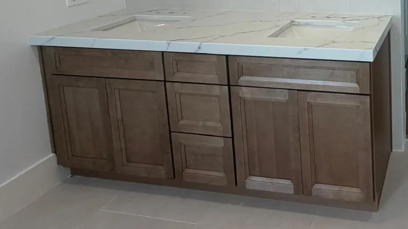 Double vanity top with two undermount sinks and drilled faucet holes on a wood cabinet