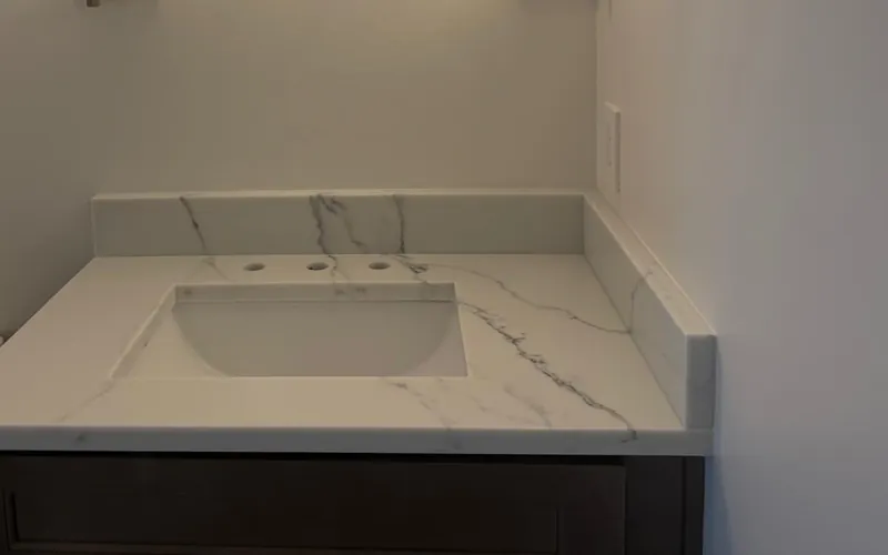 Powder room vanity with a white veined top, a matching backsplash and a dark cabinet