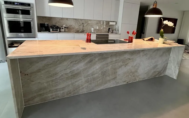 Waterfall island with soft beige veining under two pendant lights