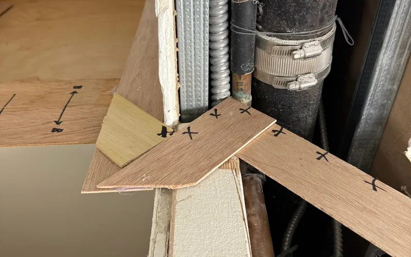 Thin wood template strips cut to fit around plumbing pipes and marked in pen