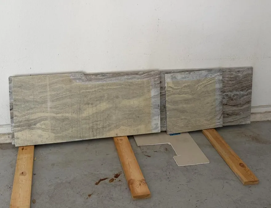 Two fabricated countertop pieces resting on wood blocks against a garage wall
