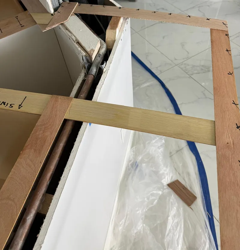 Wood template fitted around a boxed-in column on base cabinets, marked up in pen