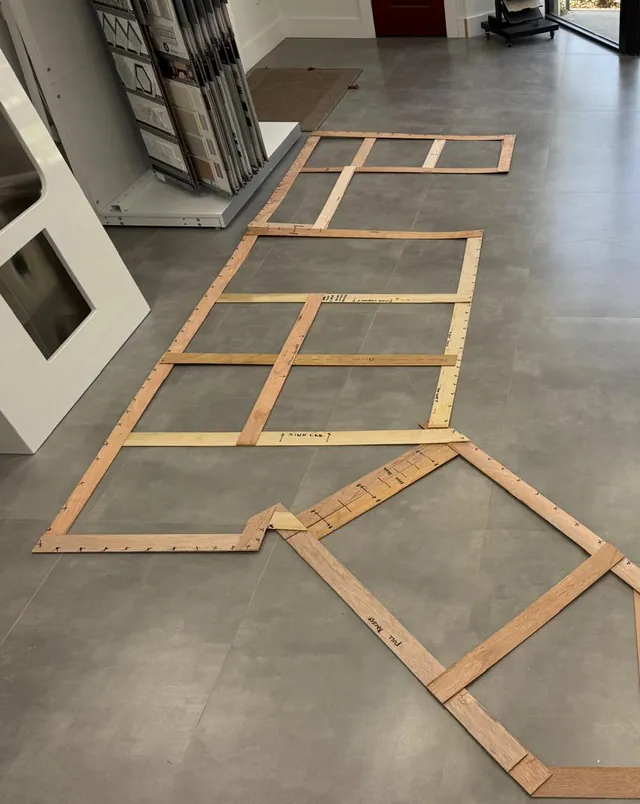 Wood countertop templates for a kitchen laid out on a showroom floor, with cabinet door samples and a display sink