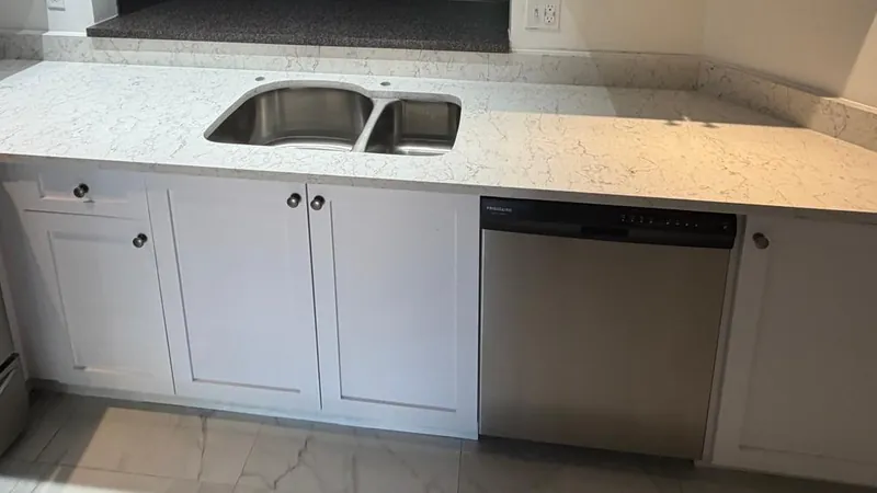 White shaker cabinets with a double-bowl undermount sink and a low stone backsplash