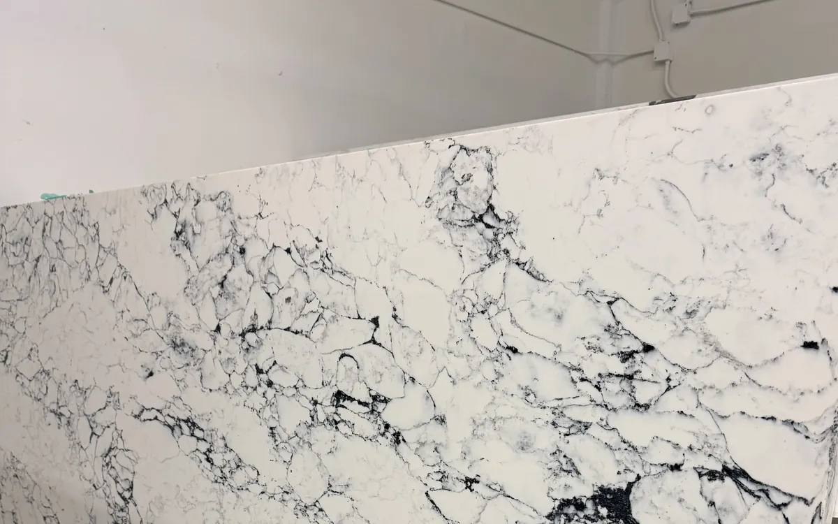 Full stone slab standing on edge against a white wall in our warehouse, its veined face turned out
