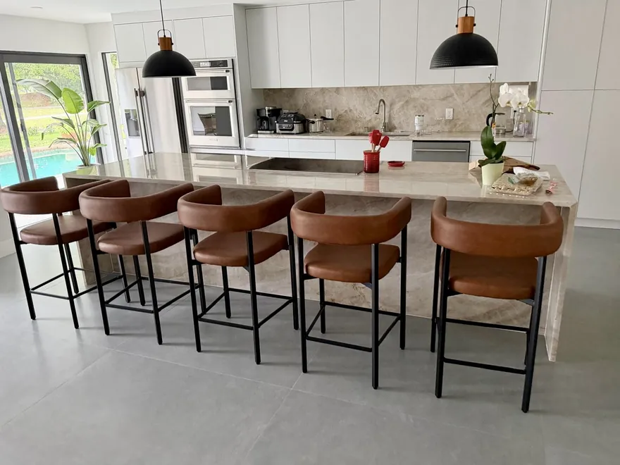 Long kitchen island with waterfall ends, a matching full-height backsplash and five leather bar stools