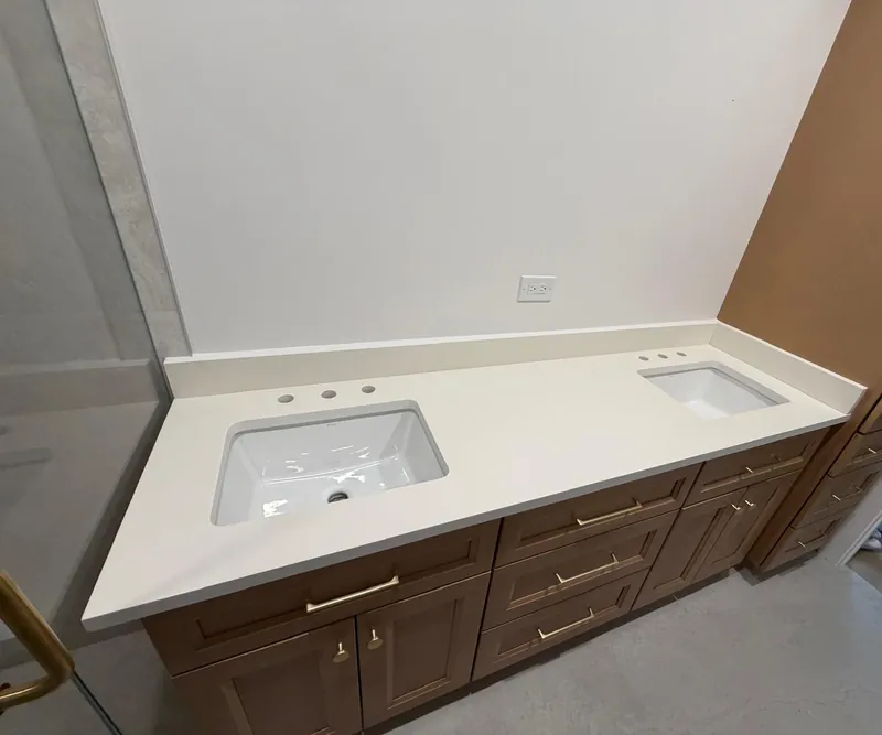 Double vanity with a white top, two undermount sinks and a low backsplash on wood cabinets
