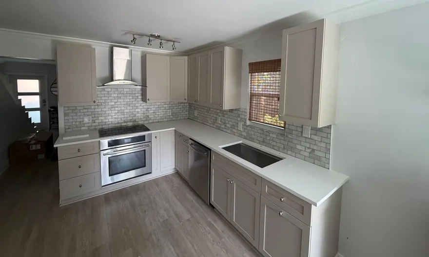 L-shaped kitchen with white countertops, an undermount sink and greige shaker cabinets