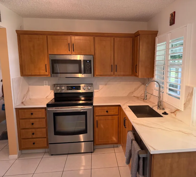 Kitchen with white, warm-veined countertops, a full-height backsplash from the same stone and maple cabinets