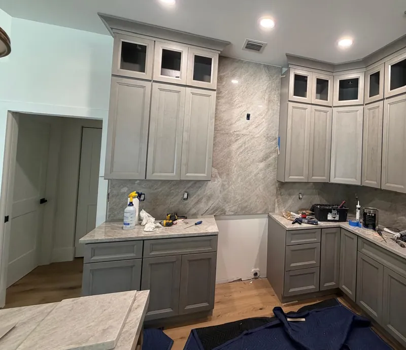 Gray kitchen with tools still on the counters and moving blankets protecting the floor