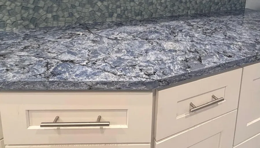 Blue veined countertop with a clipped corner on white shaker cabinets