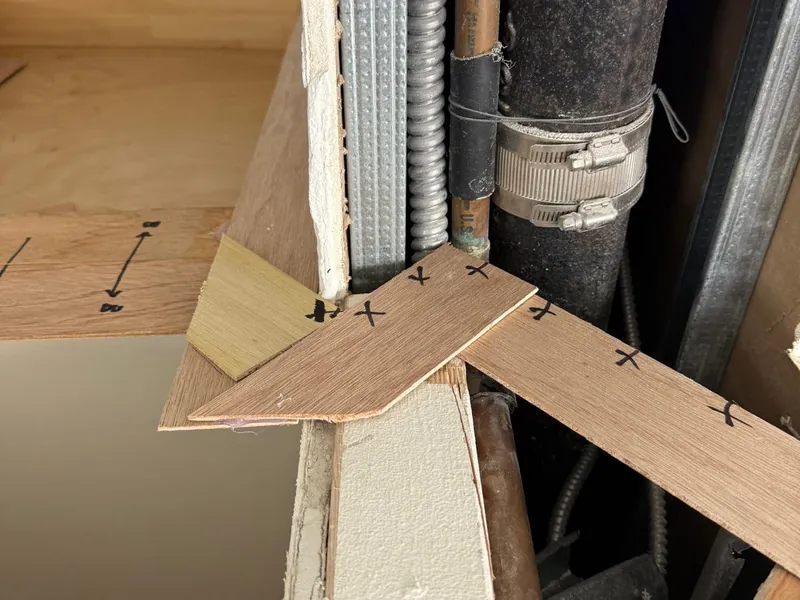 Thin wood template strips cut to fit around plumbing pipes and marked in pen