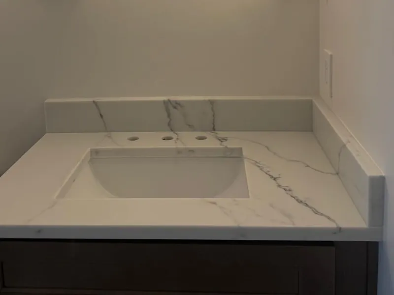 Powder room vanity top with white veining, a rectangular sink and a matching backsplash