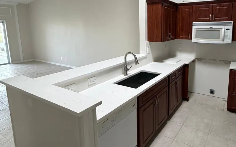 Two-level white peninsula with a raised bar ledge and an undermount sink beside dark wood cabinets