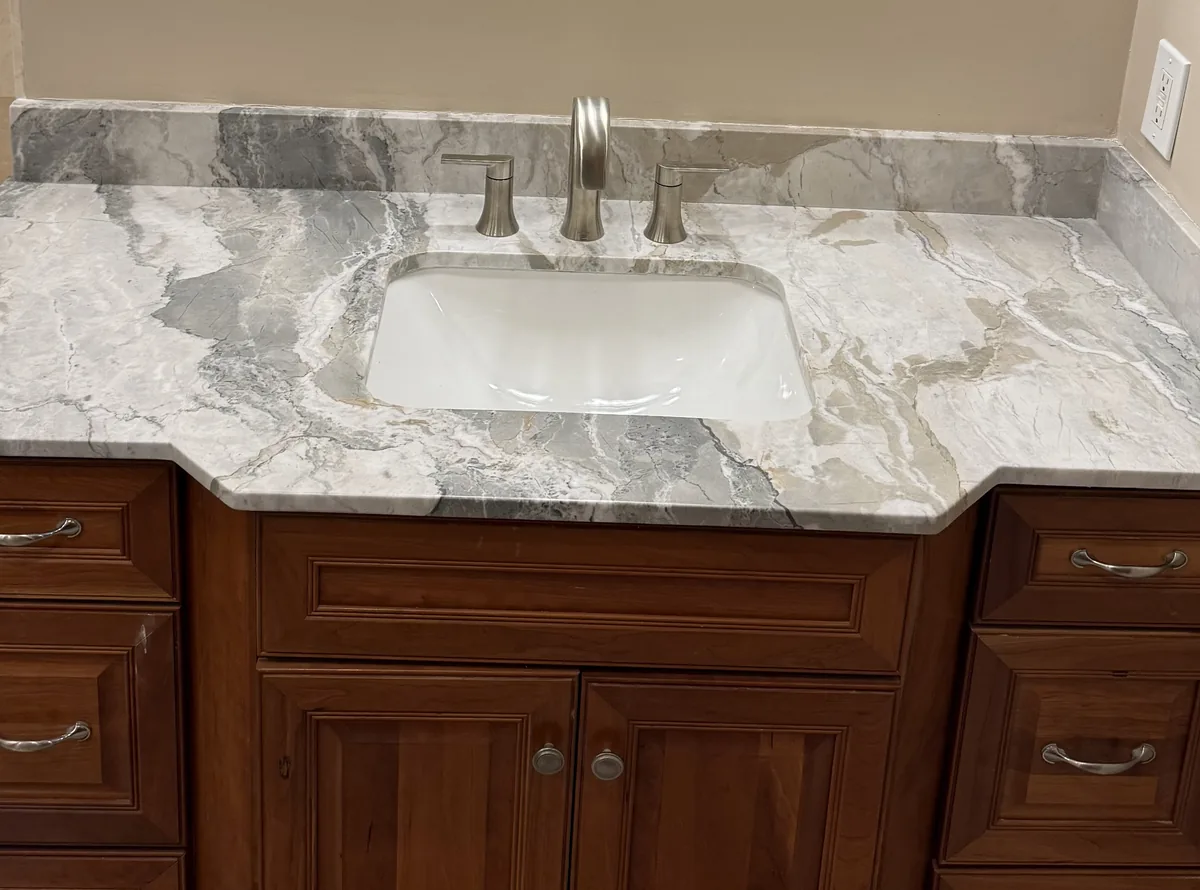 Gray and white veined vanity top with an undermount sink, a matching backsplash and wood cabinets