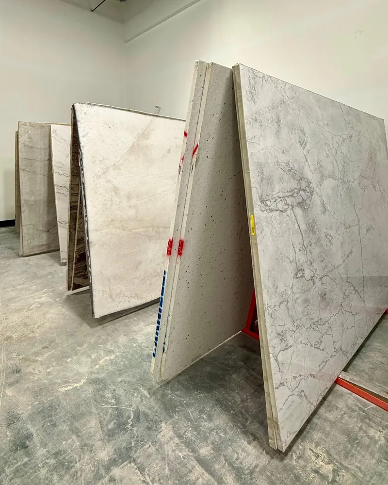 Stone slabs leaning on A-frame racks in a white-walled slab room