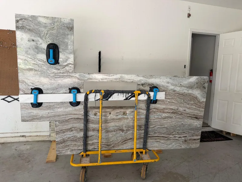 Two finished countertop sections with a sink opening, gripped by suction cups on a rolling cart