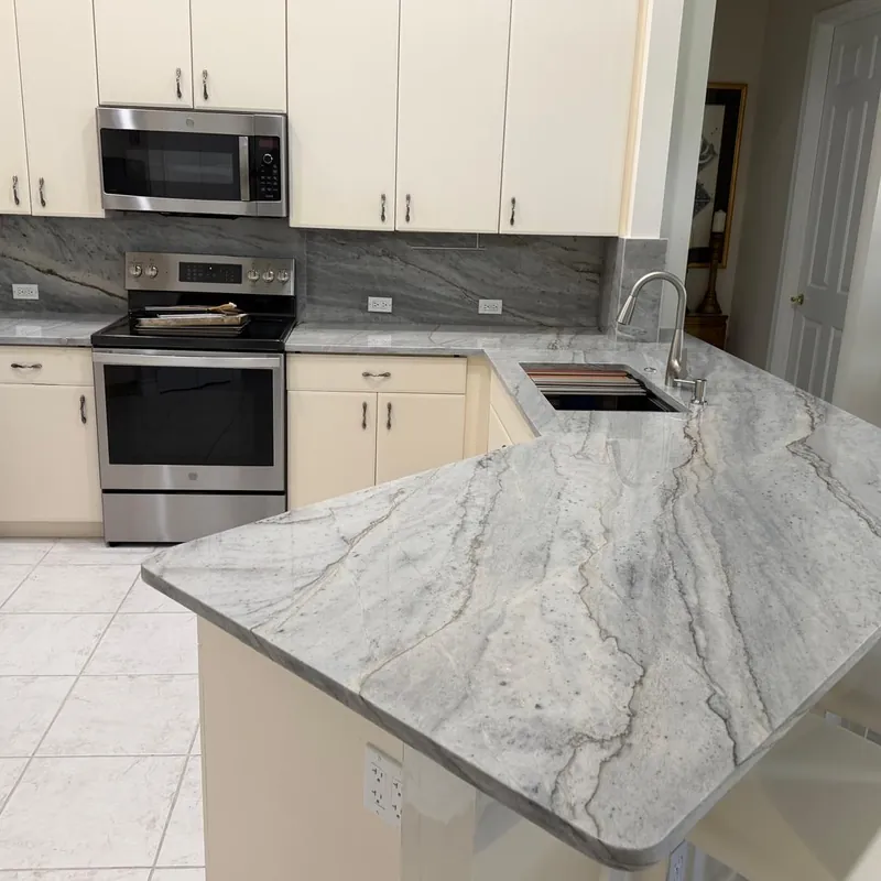 Gray veined countertop and single-level peninsula with a backsplash up to the wall cabinets