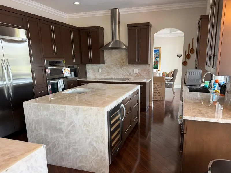 Kitchen with a light, cloud-veined waterfall island, a built-in wine cooler and dark wood cabinets
