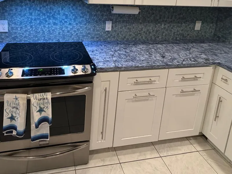 Speckled gray countertop on white shaker cabinets around a slide-in range
