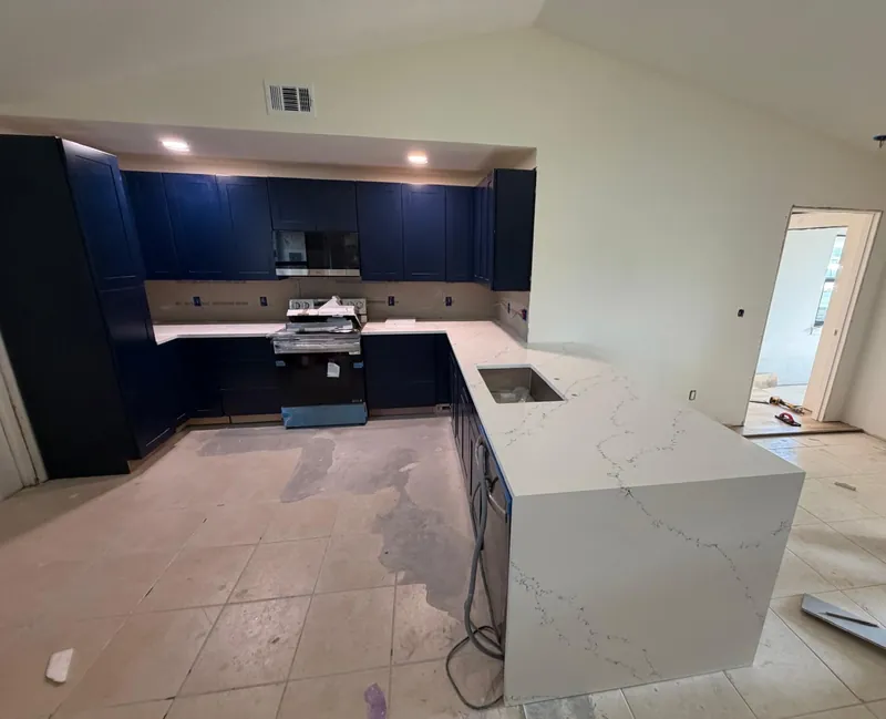 L-shaped white countertop with gray veining and a waterfall end on navy cabinets
