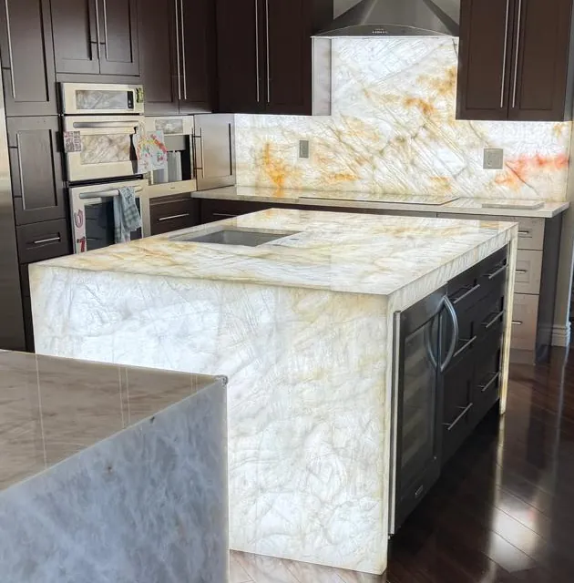 Backlit veined island with waterfall sides and a backlit full-height backsplash behind the cooktop