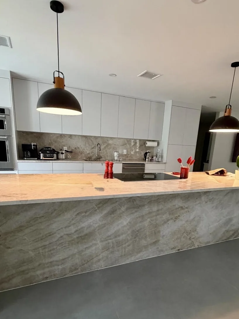 Taj Mahal quartzite kitchen island with a waterfall edge and a full-height stone backsplash