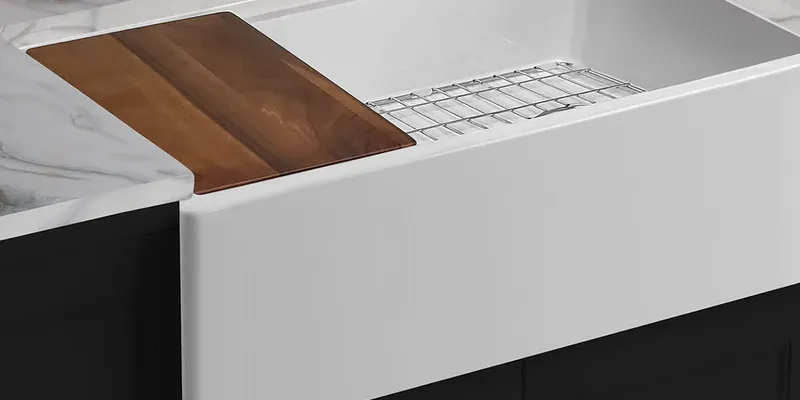 White apron-front farmhouse sink with a wooden cutting board and a bottom grid, manufacturer photo